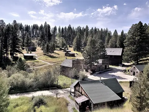 An elevated view of historic wooden buildings nestled in a mountain valley surrounded by forest.