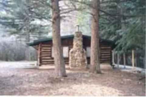 A log cabin in the woods viewed from the exterior.