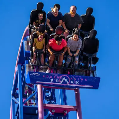 People riding a roller coaster against a clear blue sky.