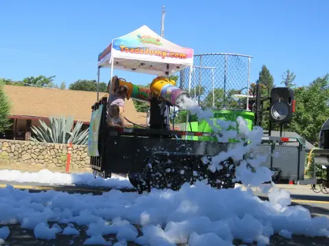 A trailer with foam cannons sprays white foam onto a street.