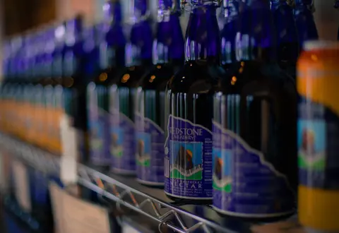 Rows of blue glass bottles with labels sit on a wire shelf.