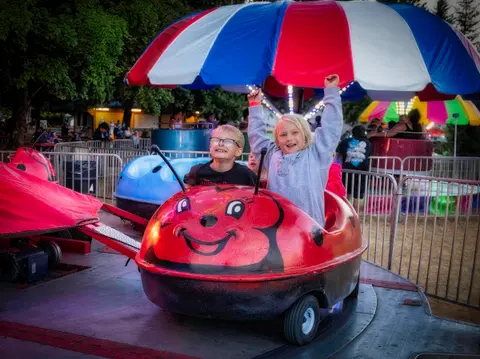 Two children riding a ladybug amusement park ride.