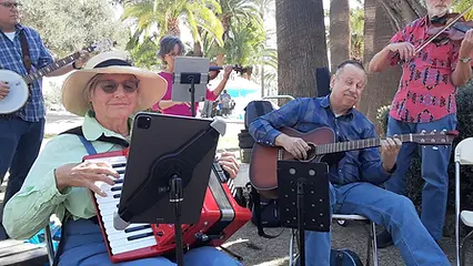A band plays music outdoors with instruments and tablets for sheet music.