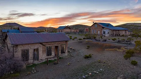 An aerial view of old historic buildings in a desert landscape during sunset.