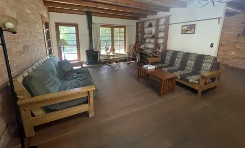 A rustic living room features exposed brick walls, wooden floors, and wooden furniture.