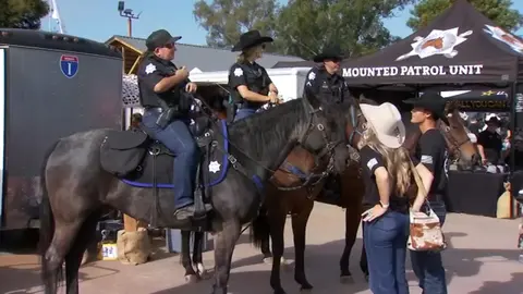 Three mounted police officers talking to people near a mounted patrol tent.