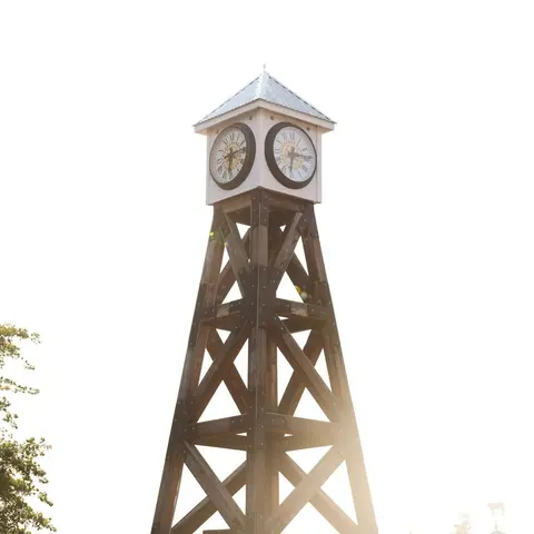 A tall wooden clock tower stands against a bright sky.