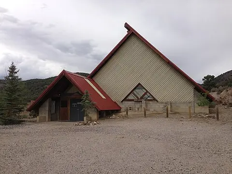 Exterior view of a unique A-frame building with a red roof.