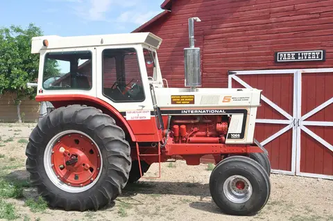 A vintage International tractor parked in front of a red barn.
