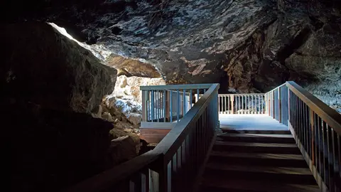 A wooden boardwalk and staircase inside a rocky cave.