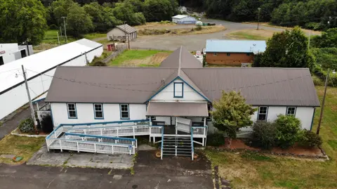 An aerial view of a white building with a brown roof and a wheelchair ramp.