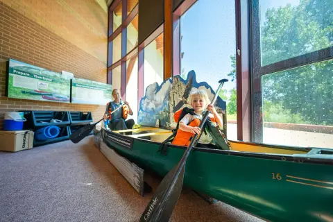 A child and a woman sit inside a display canoe.