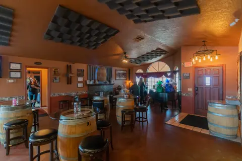The interior of a warm-toned room featuring tables made from wine barrels and stools.