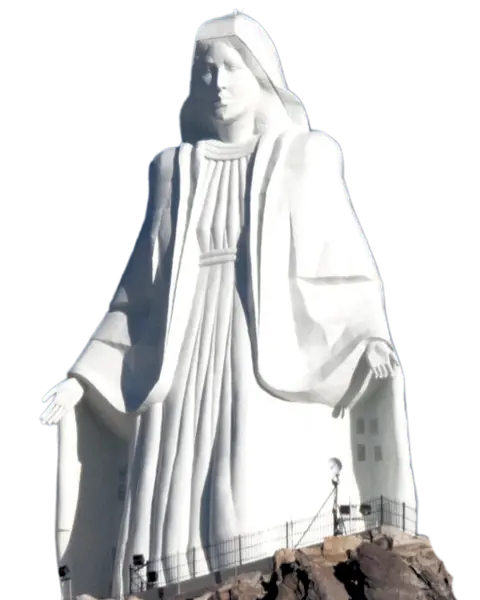 A large white statue of a robed figure stands on a rocky outcrop.