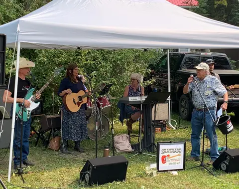 A band plays music under a white tent outdoors.