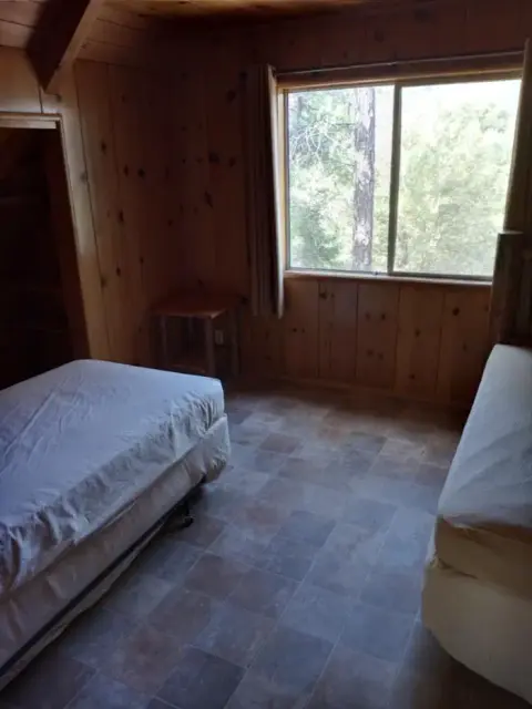 A rustic bedroom with wood-paneled walls and two beds.