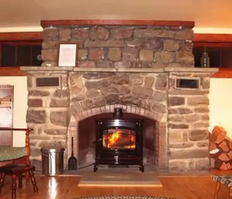 A large stone fireplace with a wood-burning stove inside it.