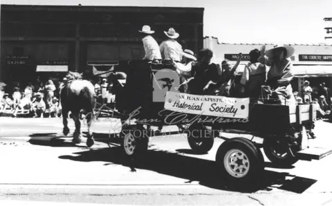 A horse-drawn wagon carrying people participates in a street parade.