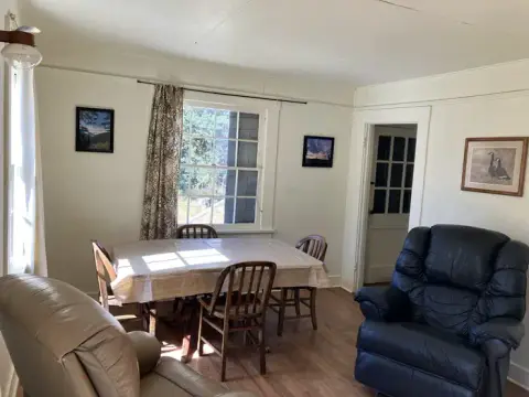 An interior shot of a room with a dining table, chairs, and armchairs.