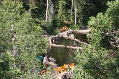 A high-angle view shows stone pools nestled in a forested hillside.