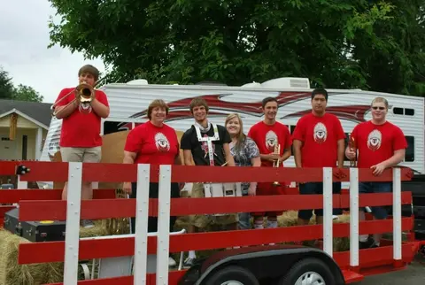 A group of students pose on a red wagon float with musical instruments.