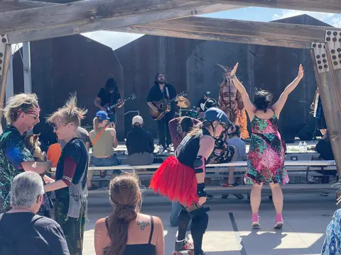 A band performs on an outdoor stage before a crowd of spectators.