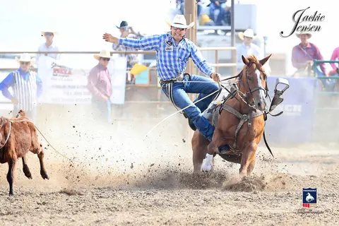 A cowboy dismounts his horse during a rodeo event.