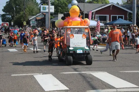 A decorated golf cart and people in a street parade.