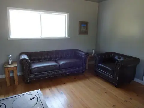 A living room with dark leather furniture and a window.