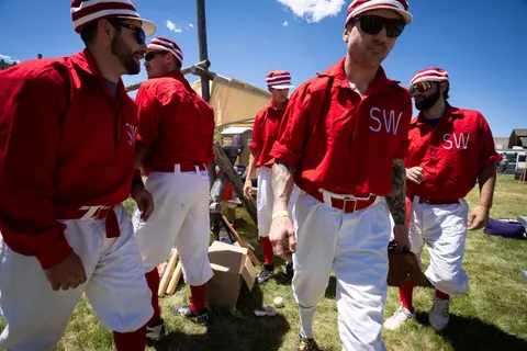 A group of people wearing vintage baseball uniforms outdoors.
