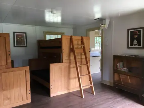 An interior view of a room with wooden bunk beds and a ladder.