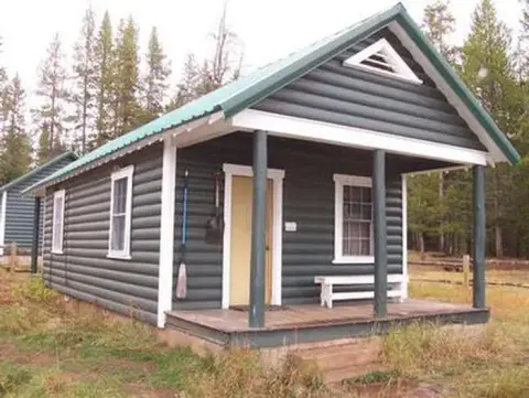 A small log cabin stands among trees.
