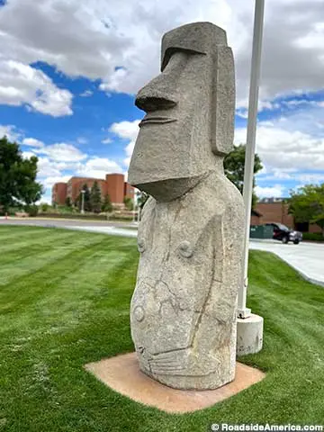 A stone moai statue stands on a green lawn.