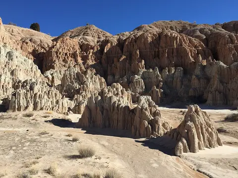 A scenic landscape featuring eroded sandstone pillars and cliffs under a blue sky.