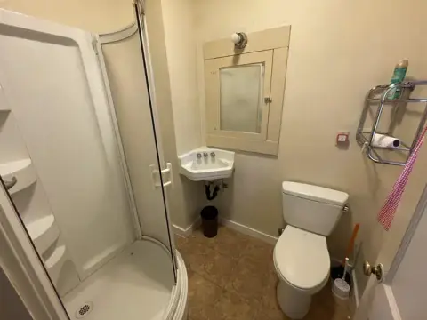A small bathroom featuring a corner shower, a corner sink, and a toilet.