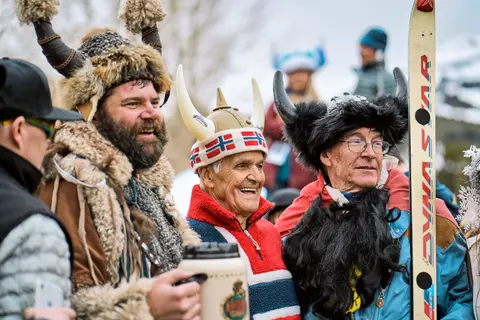 People wearing Viking-style horned hats and winter clothing outdoors.