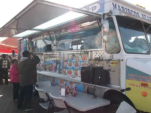 A food truck parked outdoors with a table and chairs set up next to it.