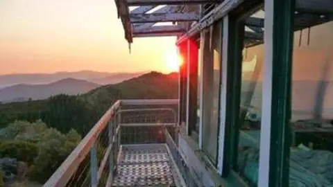 A view from the balcony of a fire lookout tower at sunset.