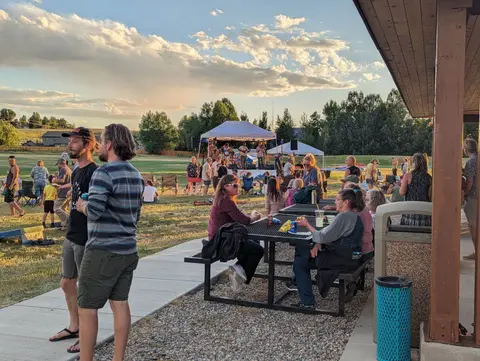 People gather at an outdoor gathering and concert on a grassy field.