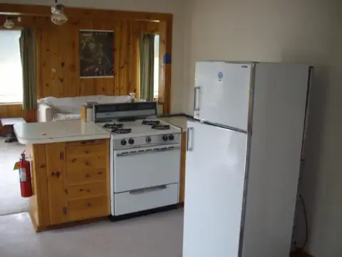A kitchen with a white refrigerator, stove, and wooden cabinetry.