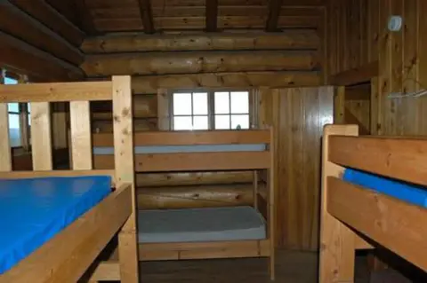 Wooden bunk beds inside a rustic log cabin.
