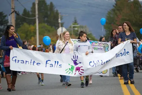 People carry a banner in a parade on a street.