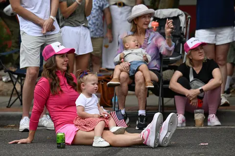 A woman and a young child sitting on the ground watching an event.