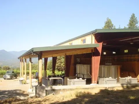 An outdoor industrial building with large metal tanks and equipment under a covered pavilion.