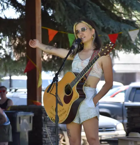 A musician performs outdoors with an acoustic guitar.