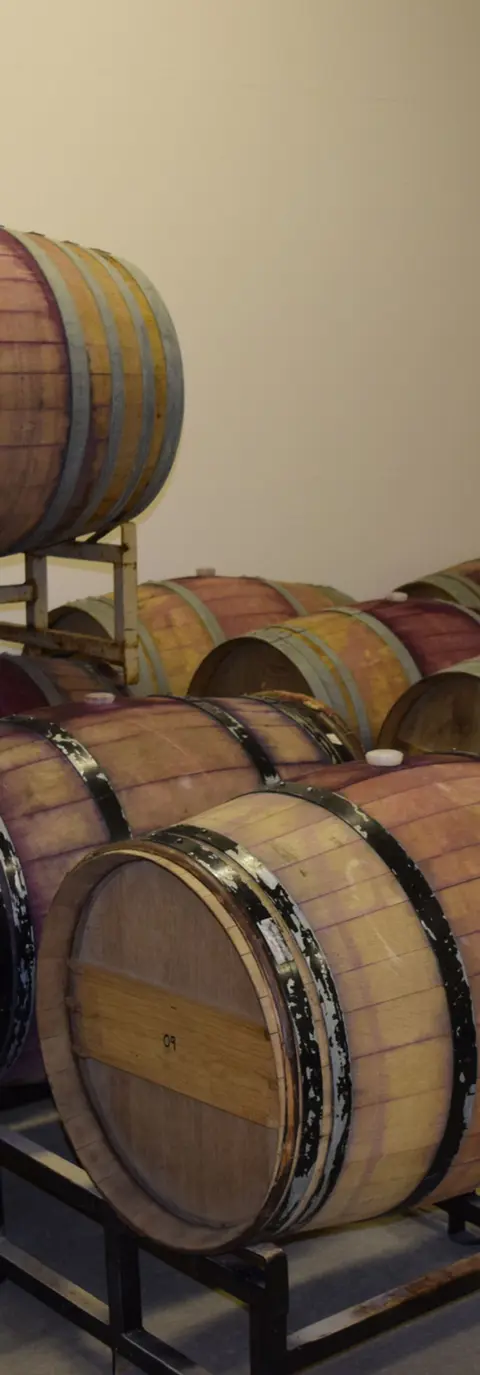 A stack of wooden wine barrels inside a room.
