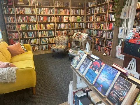 A bookstore interior with bookshelves, a yellow couch, and a display of books.