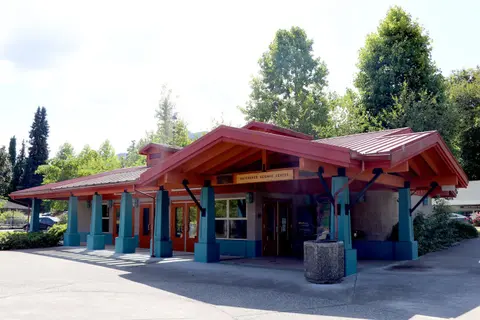 Exterior view of a modern single-story building with a red roof and blue columns.