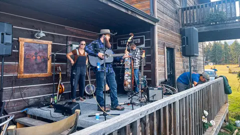 A band performs on an outdoor wooden porch stage.