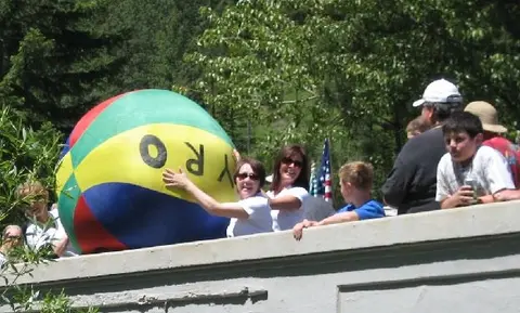 People stand behind a wall with a large colorful beach ball.
